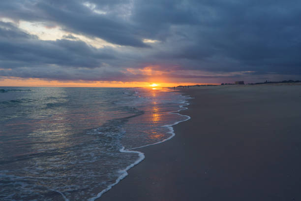istock Fiery sunset illuminates the clouds and casts a warm glow over a peaceful beach 2170220048