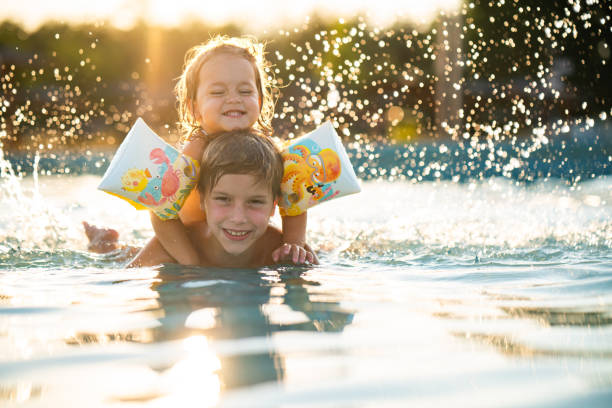istock Joyful brother and sister having fun in swimming pool 2170224770