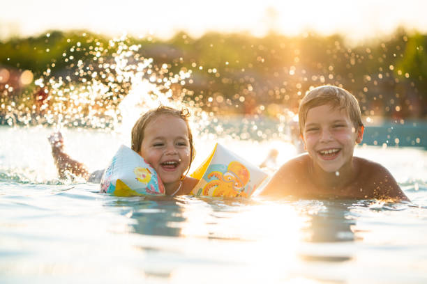 istock Cheerful siblings having fun in swimming pool 2170226855