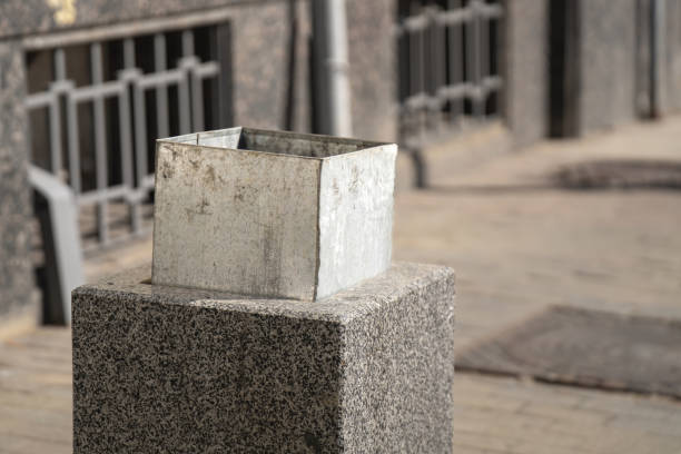 half-extended metal bucket inside a granite square bin evokes thoughts on waste and sustainability, reflecting society's ongoing struggle with consumption and environmental responsibility