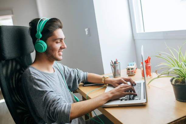 istock Young man using headphones and laptop at home 2170236973