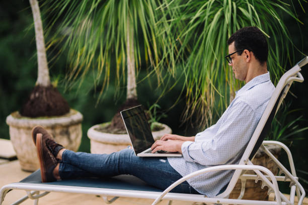 istock Mid adult man using laptop in a pool area 2170245448