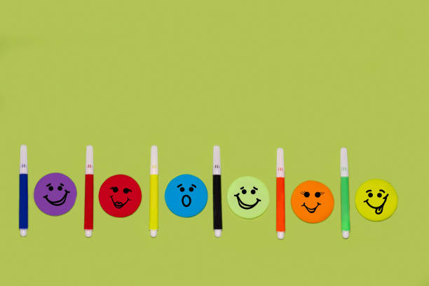 Colorful emoticons arranged in a circle with markers on a bright green background. Creativity, fun, positive, back to school, play, collaborative education