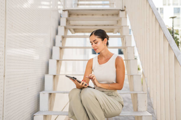 istock Young happy woman sit on stairs and use digital tablet 2170246545
