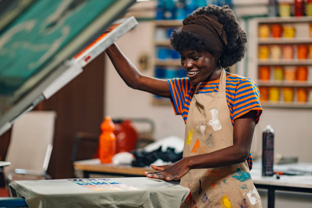 istock Smiling diverse printing shop worker looking at silkscreen printed shirt 2170248919