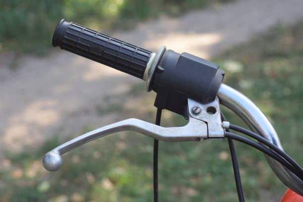 part of a old motorcycle with black gray steering wheel on the summer street