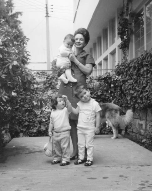image taken in the 1960s, smiling senior woman posing with her female grandchildren at her home backyard - 12 až 23 měsíců fotky - stock snímky, obrázky a fotky