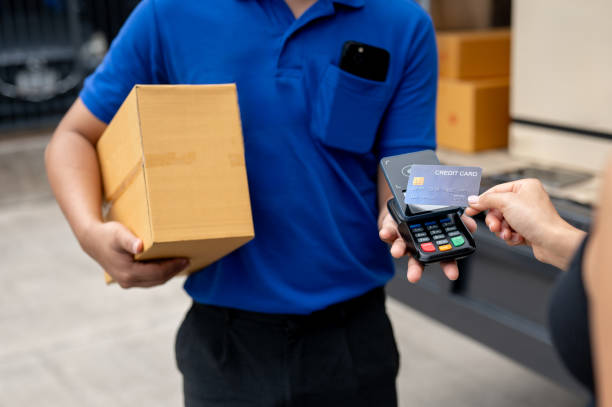 istock A customer tapping her credit card on a card reader before receiving a package from a delivery man. 2170270544