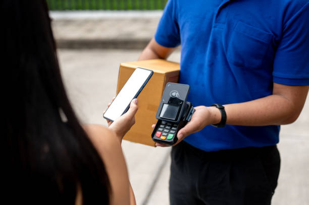 istock A customer tapping her smartphone on a card reader before receiving a package from a delivery man. 2170270554