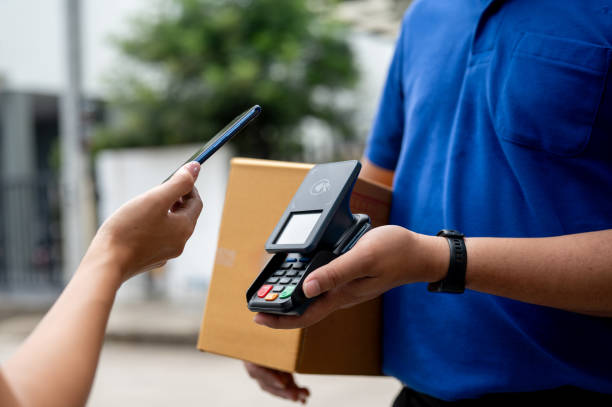 istock A customer tapping her smartphone on a card reader before receiving a package from a delivery man. 2170270564