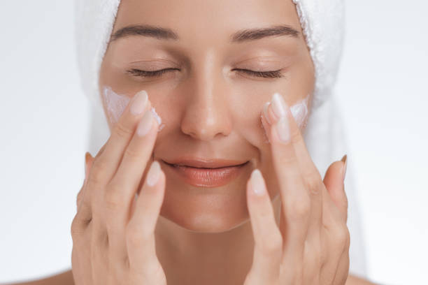 istock Serene Woman Applying Skincare Cream on Cheeks During Relaxing Beauty Routine 2170273708