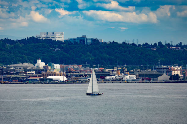 Sailboat in Puget Sound, industrial shoreline and clouds in background