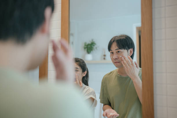 istock Young handsome young man touching his bristle on the face standing in the bathroom with a towel and looking at mirror. Preparation for daily morning routine male hygienic beauty procedure 2170274748