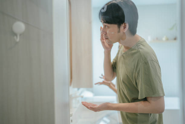 istock Young handsome young man touching his bristle on the face standing in the bathroom with a towel and looking at mirror. Preparation for daily morning routine male hygienic beauty procedure 2170274876