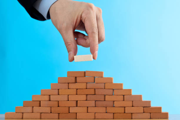 istock Businessman putting toy brick onto a pyramid 2170275475