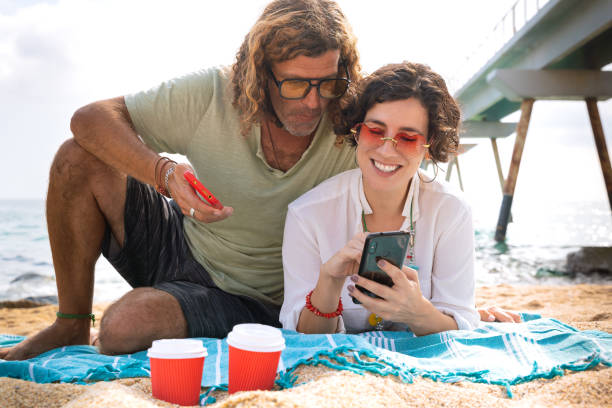 istock Smiling couple on the beach browsing smartphone apps. 2170283762