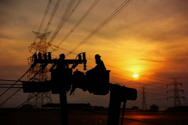 istock silhouette group of electrician workers working load on crane and lamp post on sun set sky nature background 2170283973