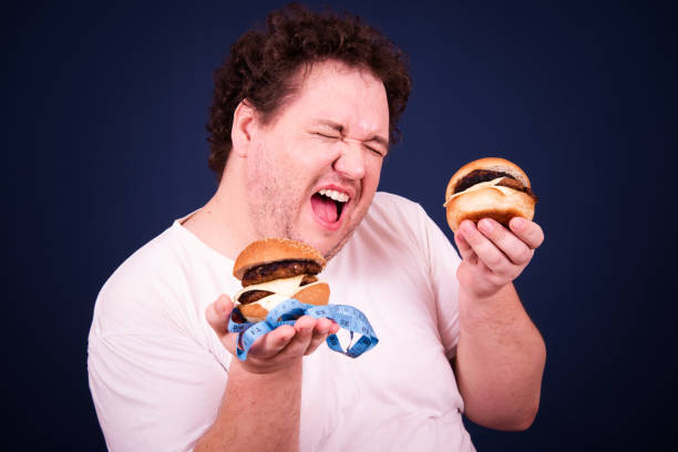 istock Funny fat man on a diet eating a burger. 2170285019