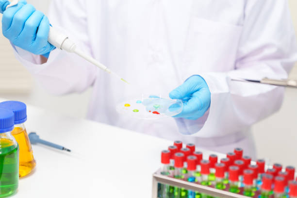 istock Two Asian scientists in lab coats sit at a table in a laboratory, examining samples through a microscope. The room is equipped with scientific tools, liquids, and chemistry materials. 2170285141