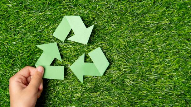 istock A child's hand holding a green paper arrow forming a triangular loop on a grassy background. 2170286394