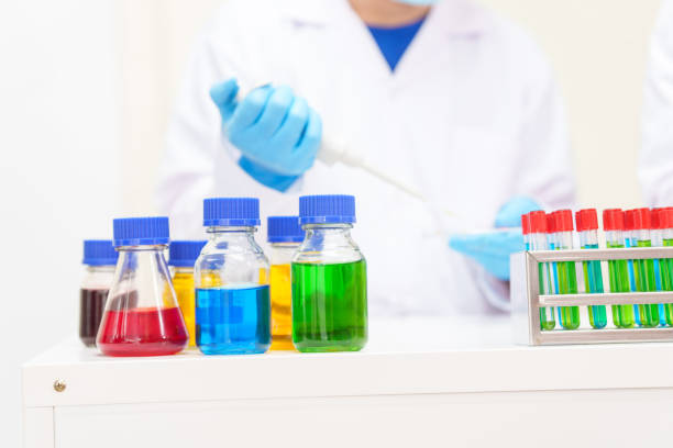 istock Two Asian scientists in lab coats sit at a table in a laboratory, examining samples through a microscope. The room is equipped with scientific tools, liquids, and chemistry materials. 2170286597