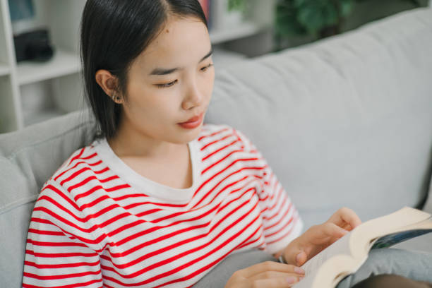 istock A relaxed young woman enjoy reading a book on a sofa at home. 2170287300