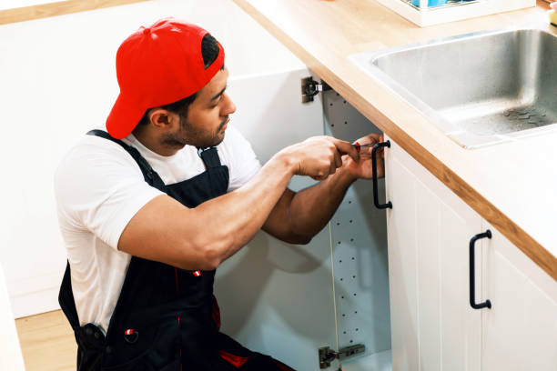 istock Asian professional plumber man work in a uniform fixing a broken water pipe problem under the sink in the client kitchen house. Indoor sink leaky repairing service. Home improvement concept. 2170291661