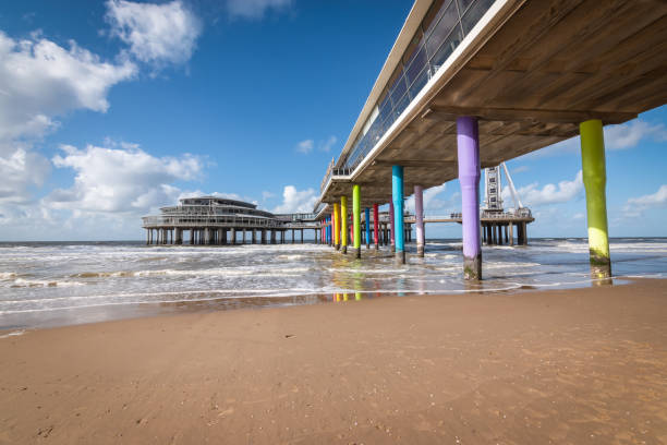 Travel image with pier and colorful pillars on the beach of Scheveningen the Netherlands on a beautiful day. No people. Summer vacation at the North Sea.