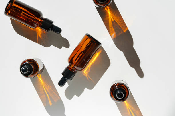 istock Arranged Amber Glass Bottles With Droppers on White Surface Accentuated by Shadows in Bright Light 2170292925