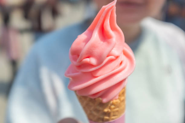 A pink strawberry flavored ice cream cone