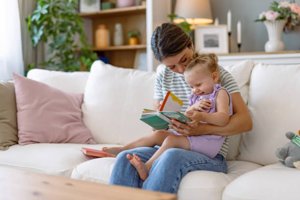 istock Mother and daughter reading together on the sofa. 2170299832