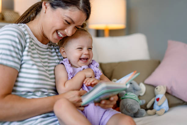 istock Mother and child laugh together while reading book. 2170299872