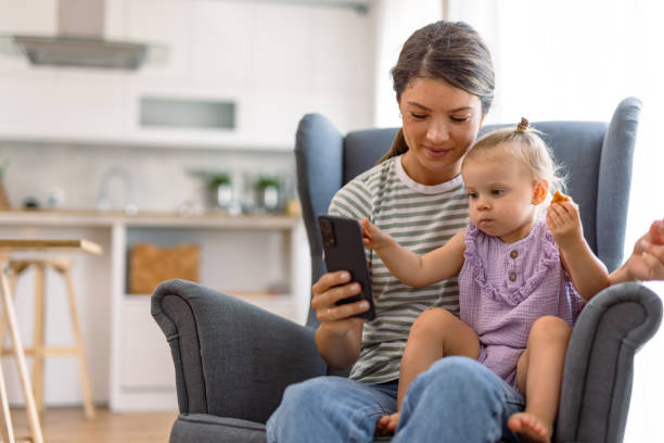 istock Mother and daughter using smartphone in cozy room 2170300149