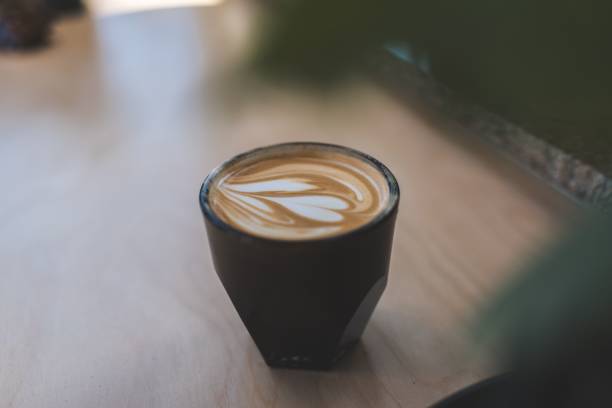 Close-up of a beautifully crafted latte with latte art in a black cup on a wooden table