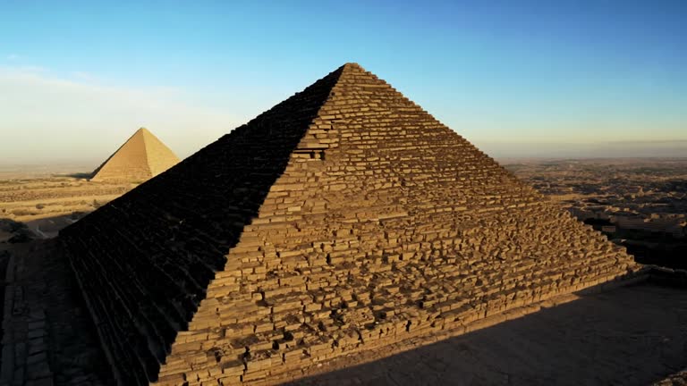 Drone pullout over the pyramids of Giza on a sunny day with clear sky in the background, in Egypt