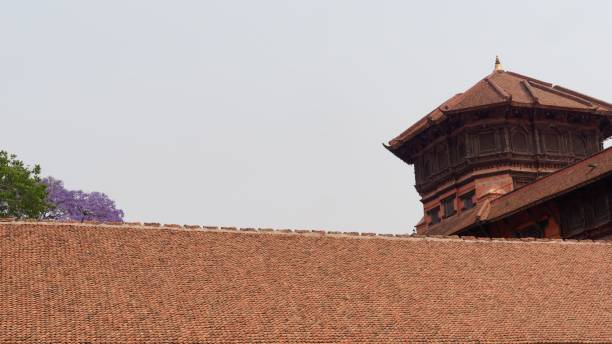 A traditional Nepalese building with a tiled roof and a clear sky in the background.
