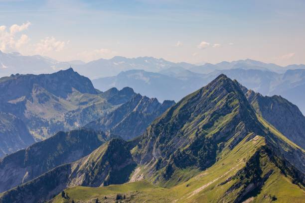 Mountain range with lush green peaks under clear blue sky.