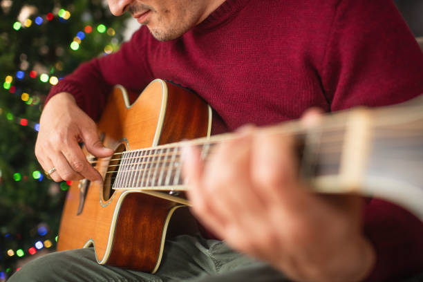 istock Mature man playing guitar near Christmas tree at home 2170305996