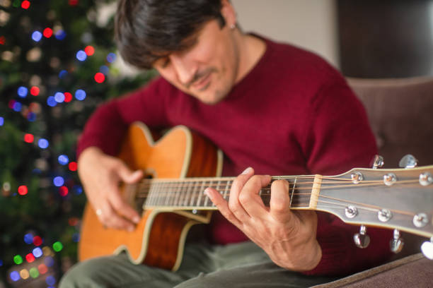 istock Mature man playing guitar near Christmas tree at home 2170306008