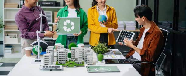 istock Asian professionals collaborate on sustainable energy solutions with wind turbines, solar panels, and eco friendly models 2170306010