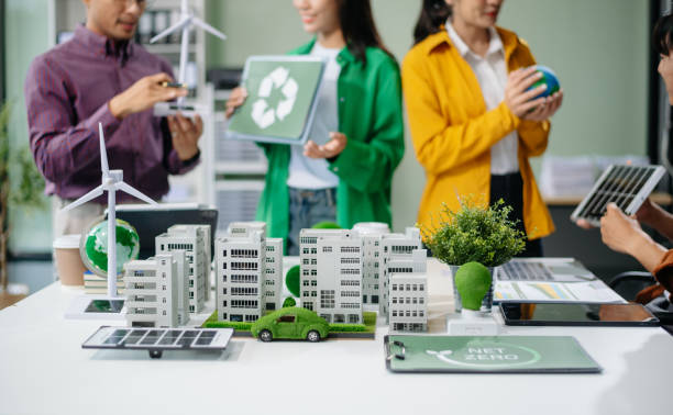 istock Asian professionals collaborate on sustainable energy solutions with wind turbines, solar panels, and eco friendly models 2170306014
