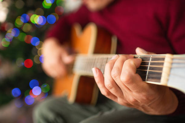 istock Mature man playing guitar near Christmas tree at home 2170306021