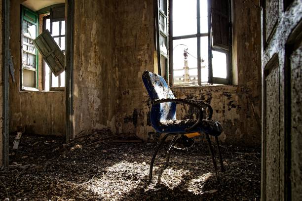 istock Abandoned room with a broken chair and open windows, with sunlight streaming in 2170306113