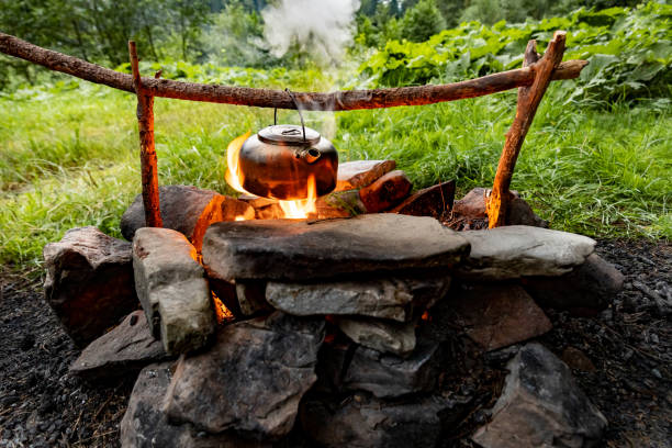 istock Making tea over an open fire in the forest. The kettle is hanging on a stick on the fire. 2170307948