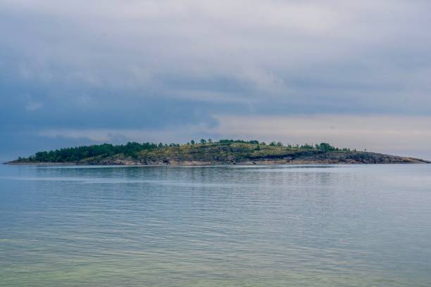 A serene view of a small island surrounded by calm waters under a cloudy sky.