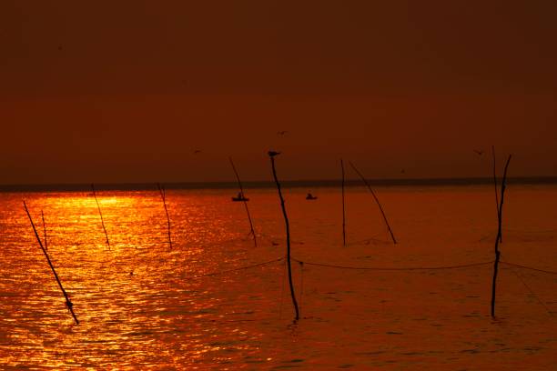 A Red-Tinted Sea at Sunset with Fishermen and Fixed Nets: A Captivating Maritime Scene