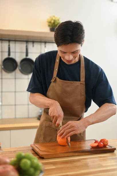 istock Handsome asian man wearing apron cutting an orange for cold refreshing drink 2170313553