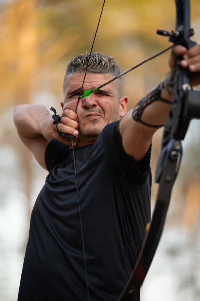 A man is holding a bow and arrow and is about to shoot it. Concept of focus and determination as the man prepares to release the arrow