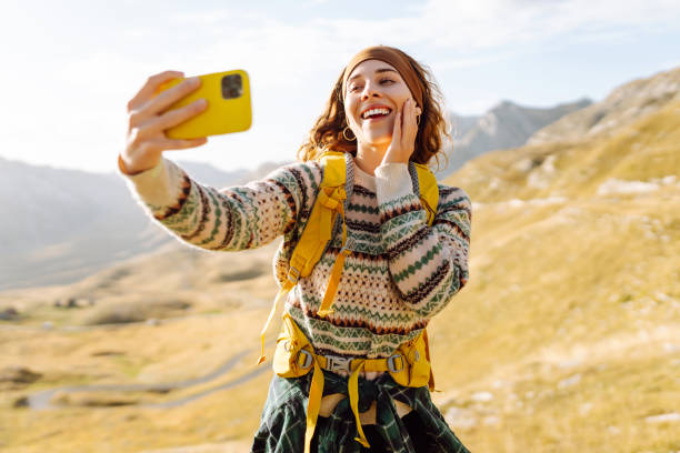 istock A young woman with a backpack is happily taking a selfie in the mountains. 2170313814