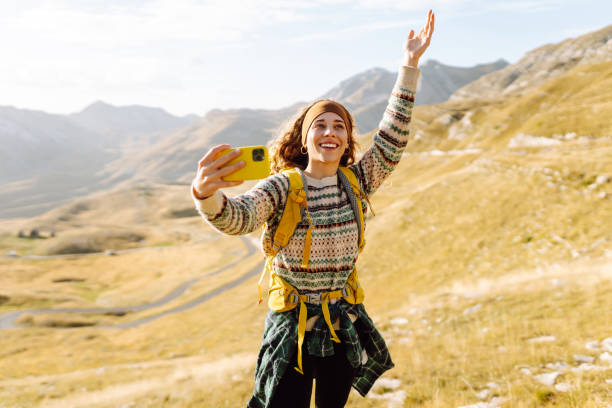 istock A young woman with a backpack is happily taking a selfie in the mountains. 2170313825